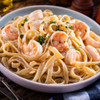 Jumbo red shrimp atop a plate of buttery fettuccine noodles.