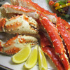 Alaska red king crab legs & claws on platter with lemon wedges.