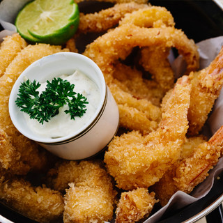 A basket  of crispy deep-fried shrimp with a simple cup of home-made tartar sauce.