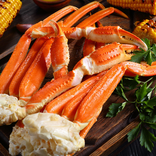 Two clusters of Alaska snow crab on cutting board with corn on the cob. Two clusters of Alaska snow crab on cutting board with corn on the cob.