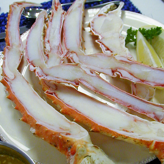Split king crab legs on a white plate with lemon wedge.