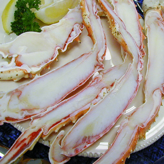 Split king crab legs on a plate with sliced lemons.