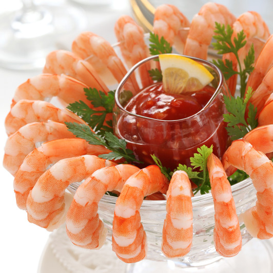 Alaska Sidestripe shrimp arranged around a glass bowl with cocktail sauce in center.