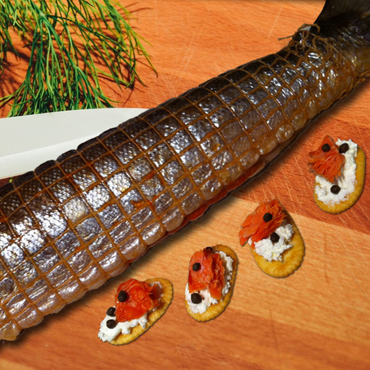 A Smoked Red-in-a-Net sockeye salmon on cutting board with appetizers crackers. A Smoked Red-in-a-Net sockeye salmon on cutting board with appetizers crackers.