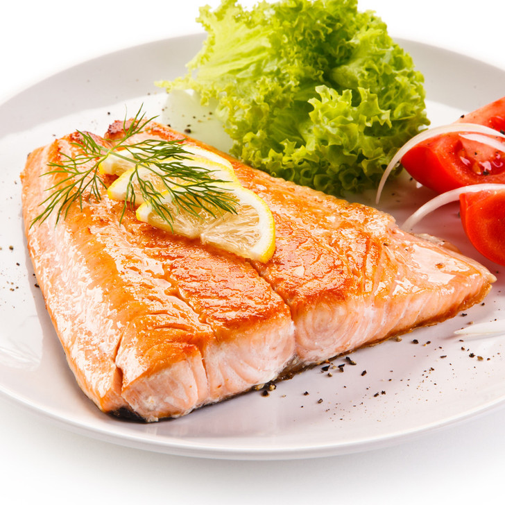 An Alaska king salmon tail portion topped with sliced lemons.