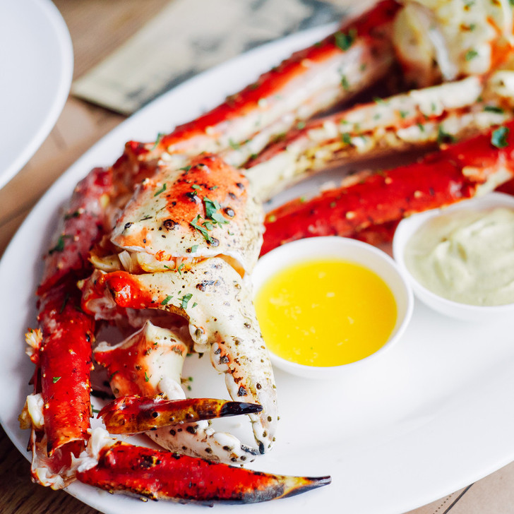 Giant king crab legs on a large white oval plate with melted butter.