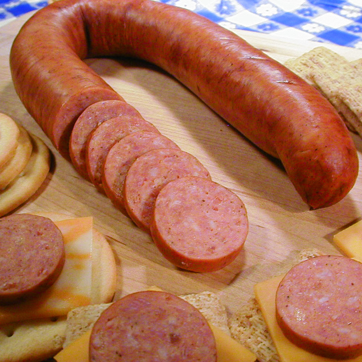 A partially sliced Alaska reindeer sausage link with cracker & cheese appetizers.