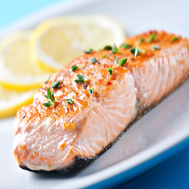 A delicious Alaska coho salmon fillet portion with lemon slices.