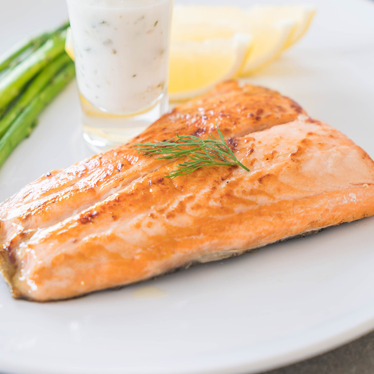 A wild Alaska Coho salmon tail portion with tartar sauce, sliced lemons, & asparagus.