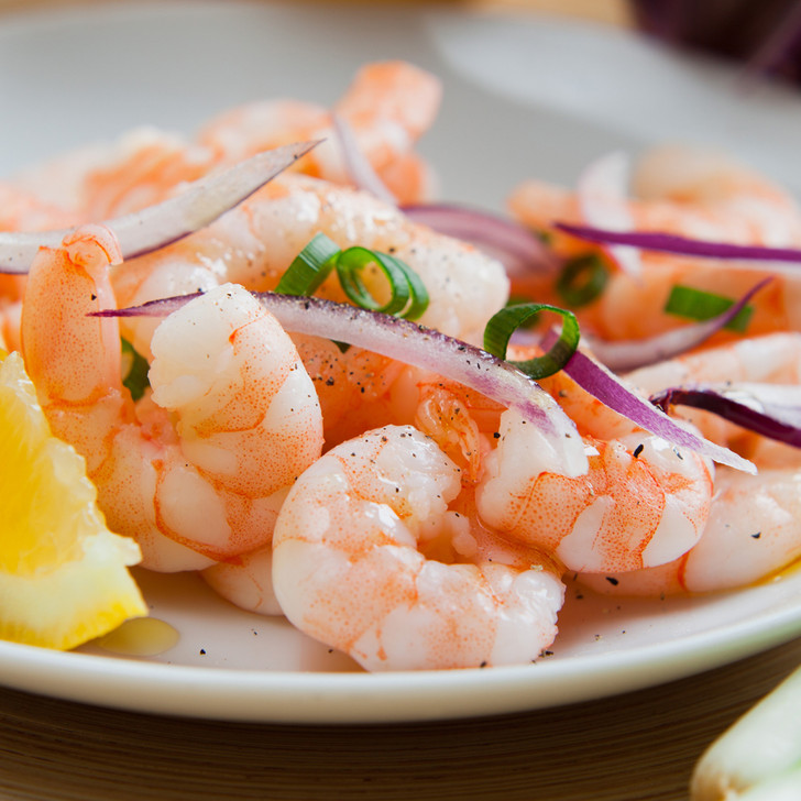 Peeled Argentine red shrimp with lemon and onion slices.