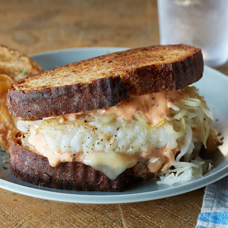 A thick Alaska halibut reuben sandwich on toasted rye bread