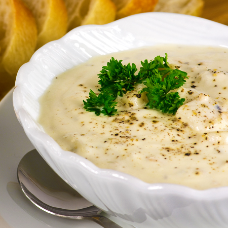 A rich bowl of clam chowder sprinkled with pepper and garnished with parsely