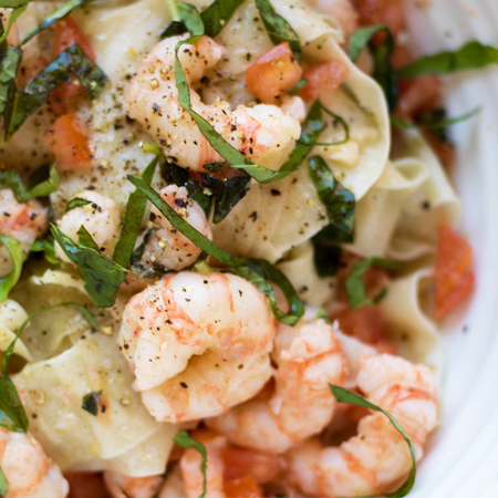 Garlic butter spot prawns mixed with tomatoes, basil, & noodles