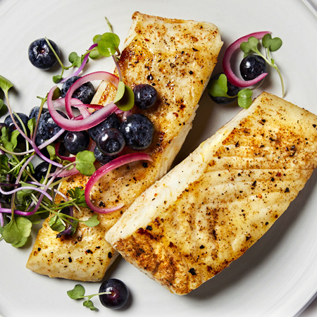 Two seared halibut fillets with fresh blueberries & sliced red onions