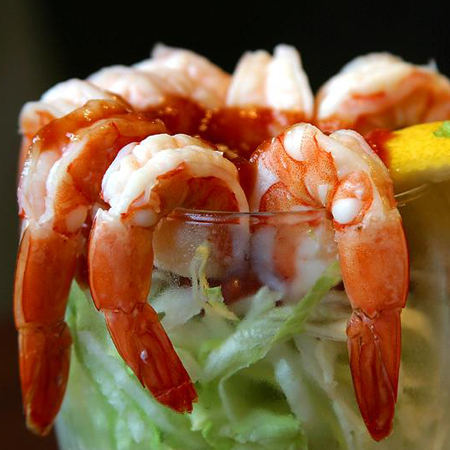 Delicious shrimp hanging on side of cocktail glass with lemon & lettuce