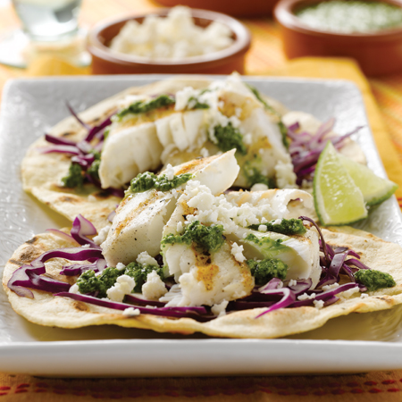 Charred tortillas with halibut & cilantro pesto on top sprinkled with cheese & cabbage shavings