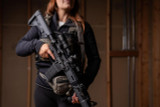 Woman holding a BCM rifle with mounted Nightforce Optics NX6 1-6x24mm riflescope in black 1.54 Ultramount inside of a dark building (C727, C728).