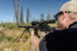Man shooting Aero Precision Solus Rifle mounted with Nightforce Optics NX6 6-36x56mm F1 in black X-Treme Duty Ultralite 1.0" 4-screw rings from a tripod outdoors (C745, C746, C747, C748).
