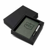 A green notebook and silver pen set in a black gift box, featuring a logo on the notebook.