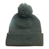 A dark grey knitted beanie featuring a pom pom on top and a folded cuff. It has a branding logo.