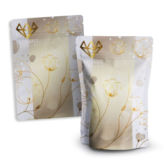 A small foil stand-up pouch in white and gold with a floral design and a logo.