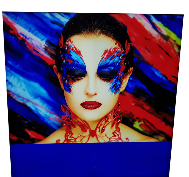 A decorative light box featuring a woman with vibrant blue and red face paint against a colourful, abstract background.