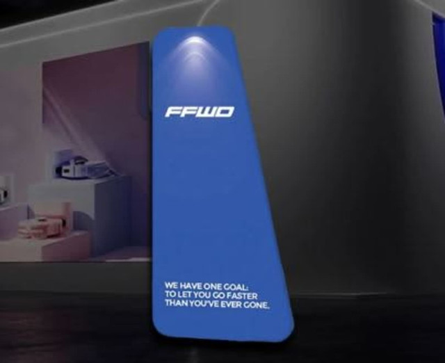 A blue, triangular tension fabric display with a light at the top and a logo. The display has a sleek design.