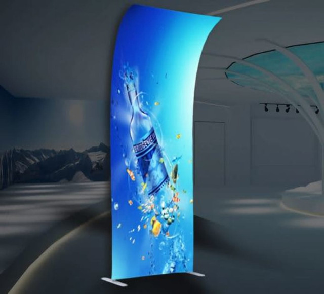 A tension fabric display featuring a vibrant blue design with a water bottle and splashes, set in a modern indoor space.