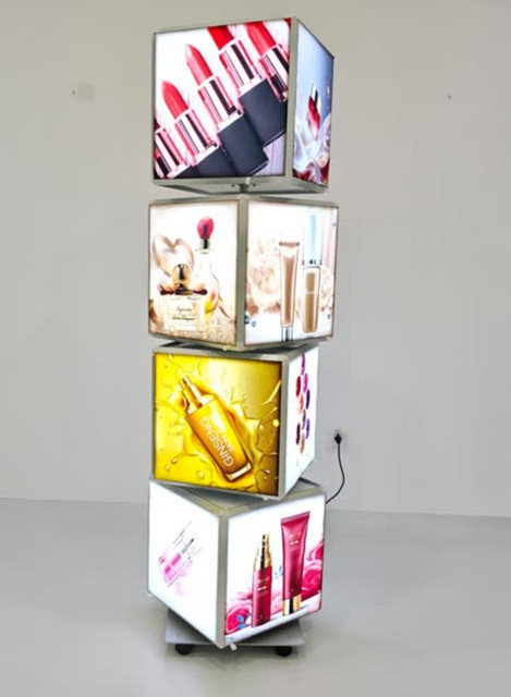 A rotating light box displaying vibrant cosmetic advertisements in various colours, featuring four illuminated panels.