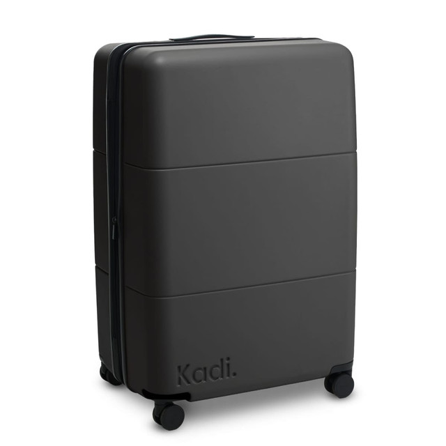 A large black suitcase with a smooth exterior and wheels, featuring a brand logo on the side.
