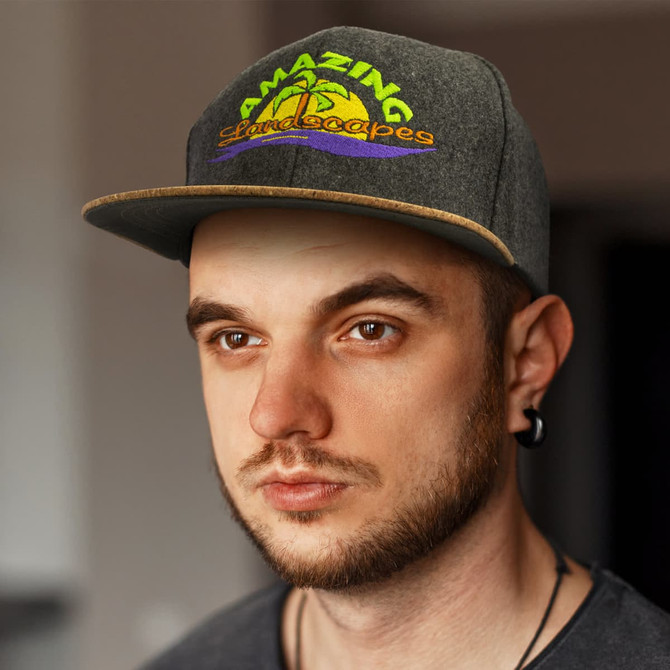 A flat peak cap in grey with a colourful logo on the front, featuring a blend of green, yellow, and purple.
