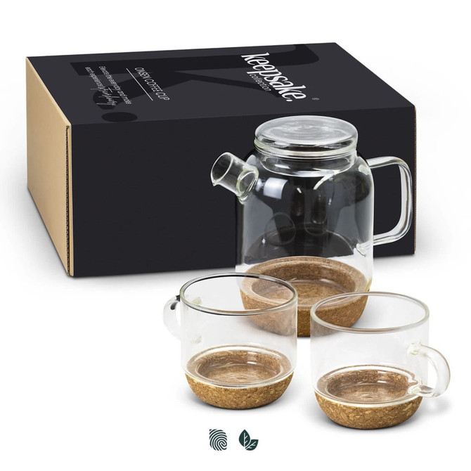 A glass tea pot with two glass cups, featuring a cork base, displayed beside a branded box.