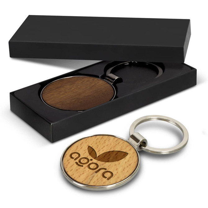 A round wooden key ring with a metallic keychain, presented in a black gift box.