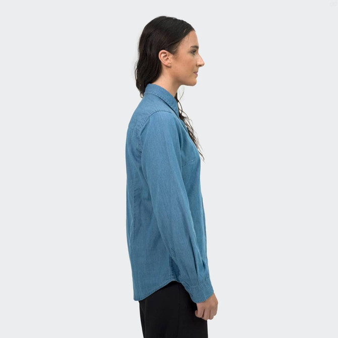 A women's denim button-up shirt in a light blue shade, displayed from the side view, featuring a collar and long sleeves.