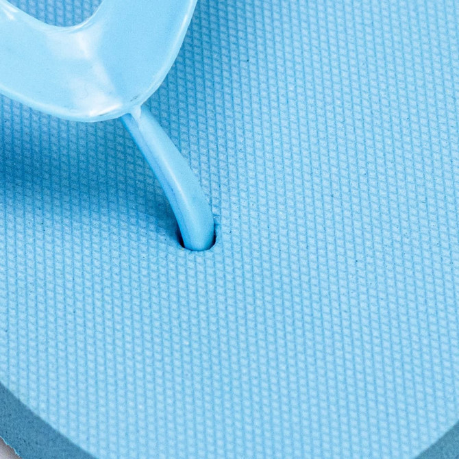 A close-up of a light blue Tidal Flip Flop with a thong strap and textured footbed. Features a logo.