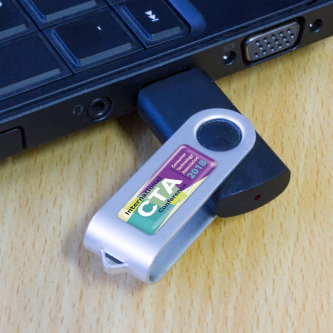 A USB flash drive plugged into a laptop, featuring a silver casing with a logo and text on the side.
