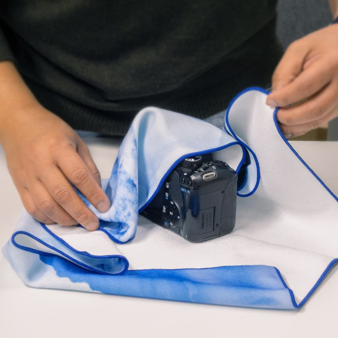 A large, blue and white patterned cloth is being used to cover a camera on a table.