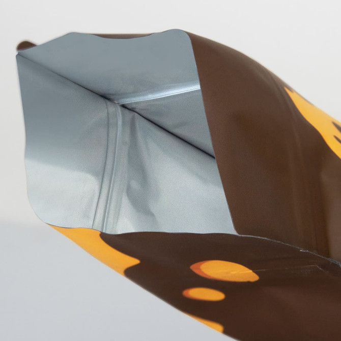 A small foil flat bottom pouch in brown and silver with a logo feature.