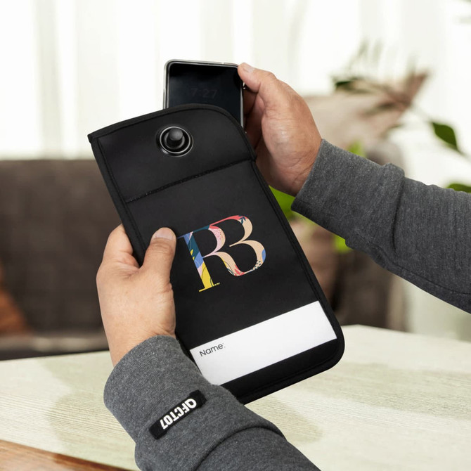 A black lockable phone pouch with a logo, being held with a smartphone partially inserted.