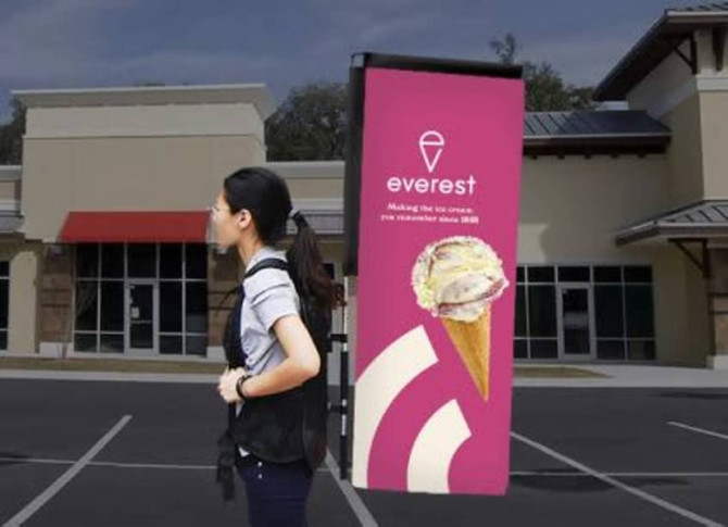 A small double-sided backpack wing banner in vibrant pink, displaying a logo and an ice cream graphic.