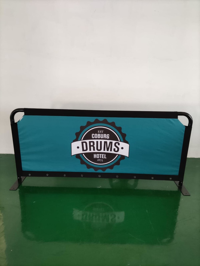 A teal crowd barrier featuring a black frame and a logo in the centre.