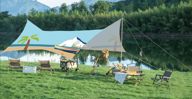 A camping canopy featuring a light blue design with palm trees, set up near a serene lake and grassy area.