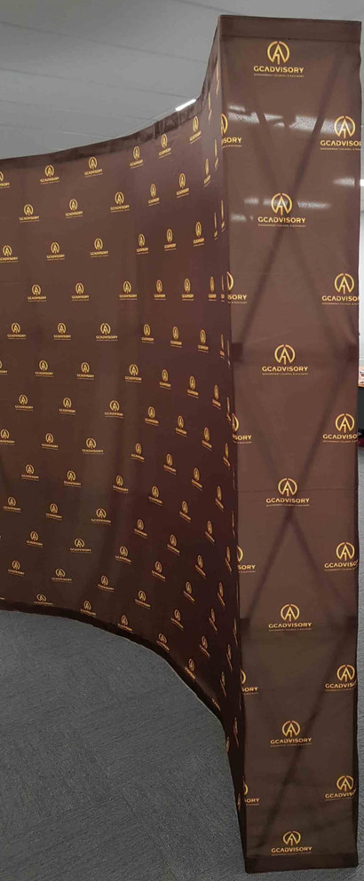 A curved promotional backdrop featuring a brown design and a logo in a repeating pattern.