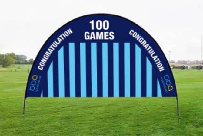 A blue arch banner with vertical stripes and a logo, featuring "100 GAMES" and "CONGRATULATION" text.