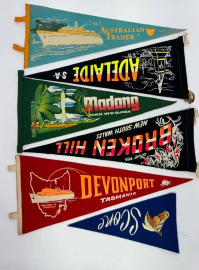 Felt pennants in various colours featuring illustrations and text from different locations and events.