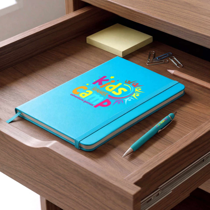 A blue notebook with a colourful design and a turquoise pen are placed on a wooden desk drawer.
