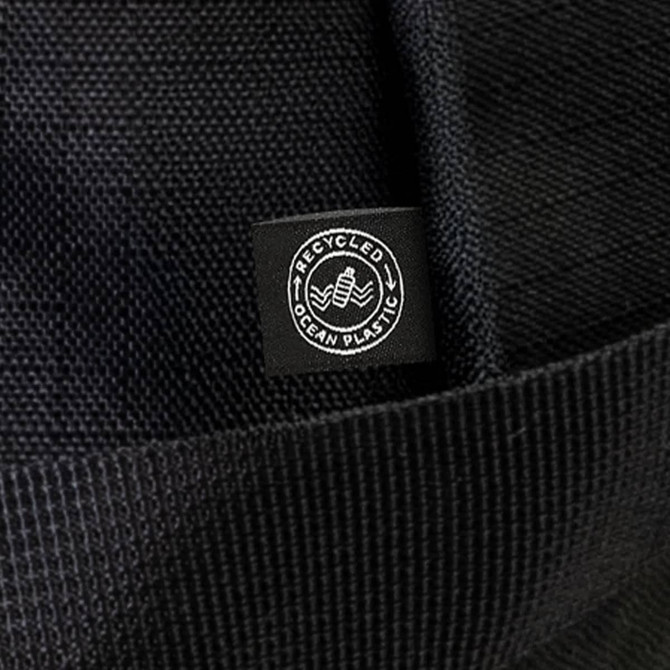 A black duffle bag made from recycled ocean plastic, featuring a small logo tag.