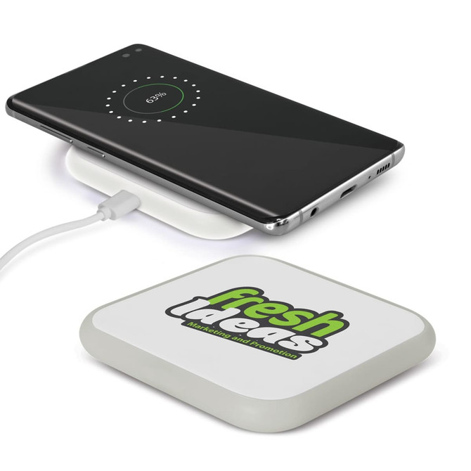 A square wireless charger in white with a logo, displaying a phone charging on top.
