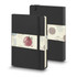 A large black hard cover notebook with an elastic band and decorative sleeve, featuring a logo.