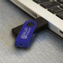 A blue and black USB flash drive partially inserted into a laptop USB port, featuring a logo.